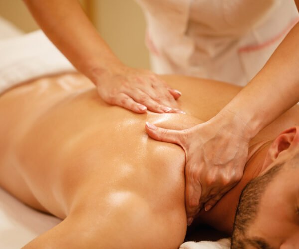 Close-up of man having back massage during spa treatment at wellness center.
